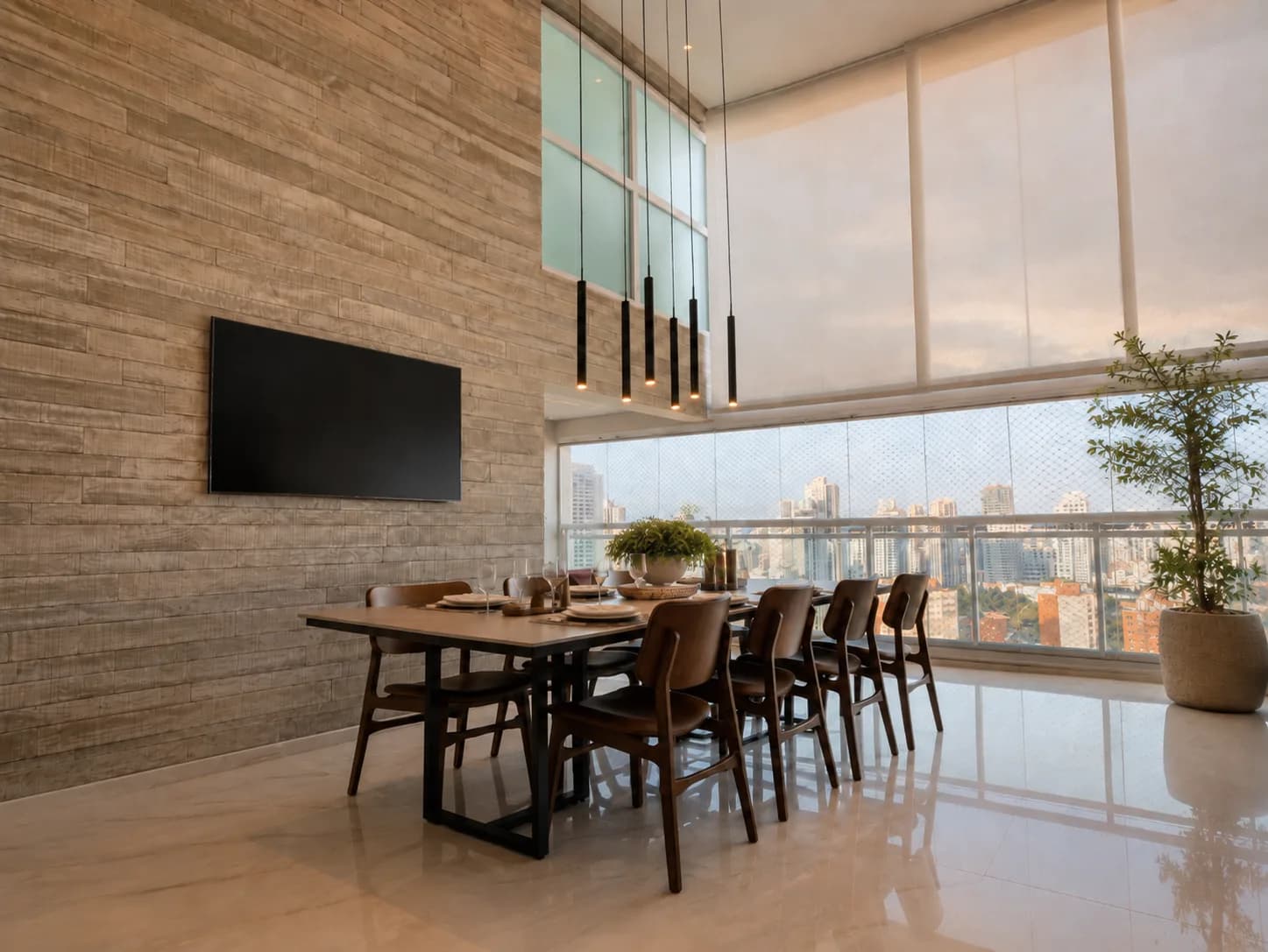 Mesa de jantar para oito diante da parede de pedra com TV e das janelas com vista para a cidade