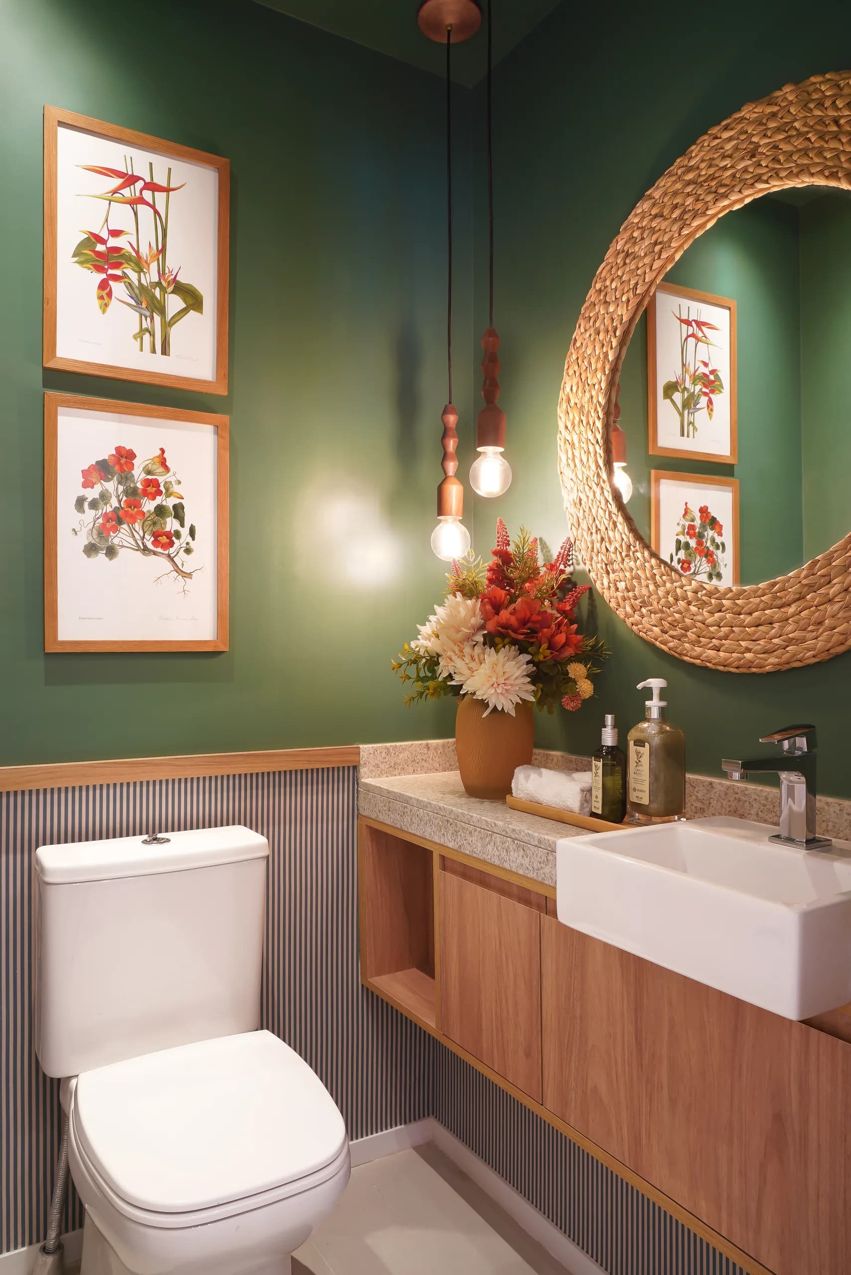 Lavabo com parede verde, espelho redondo de palhinha, cuba de apoio e gravuras botânicas
